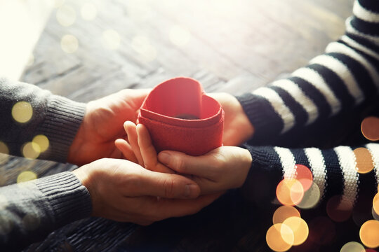 Woman holding hands with red heart on wooden background, top view