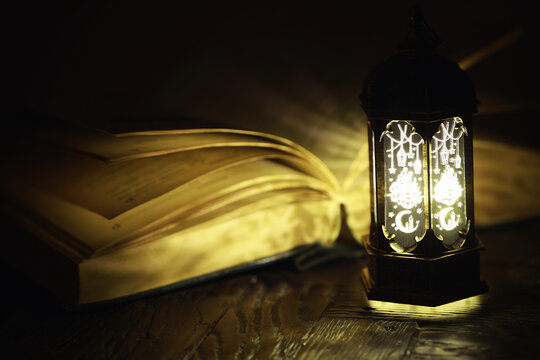 Ornamental Arabic lantern with burning candle glowing at night. Festive greeting card, invitation for Muslim holy month Ramadan Kareem.