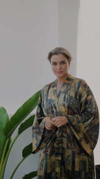 Elegant woman wearing luxury kimono robe in modern tropical home.