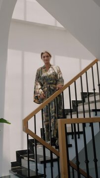 Elegant woman wearing luxury kimono robe in modern tropical home.
