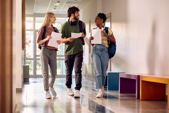 Group of happy college students with test results walking through the hallway..