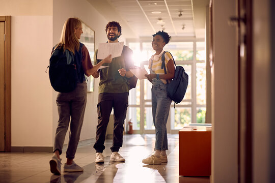 Happy college friends with test results in hallway.