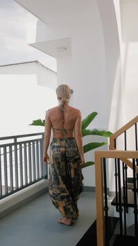 Woman models coordinated patterned resort wear with halter bikini top and flowing wide leg pants 