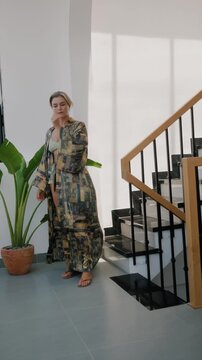 Elegant woman wearing luxury kimono robe in modern tropical home.