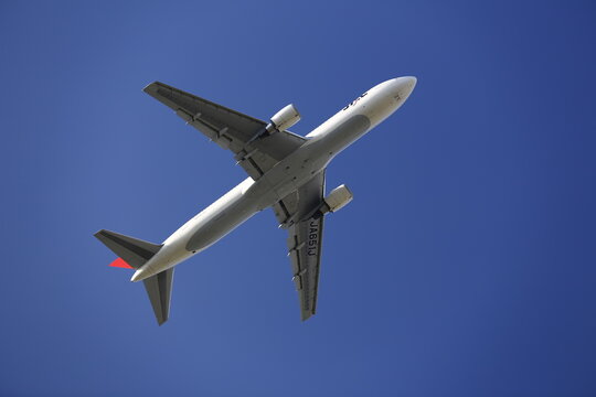 A Japan Airlines Passenger Jet Flies Overhead.