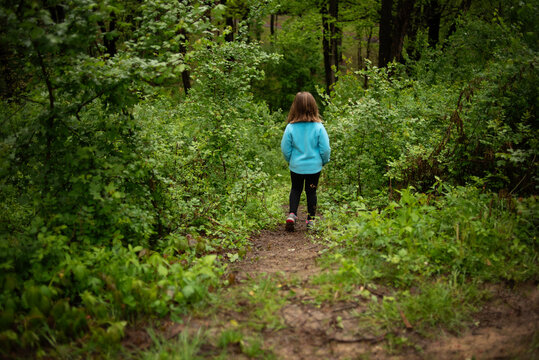 Little girl looking down a path in the woods