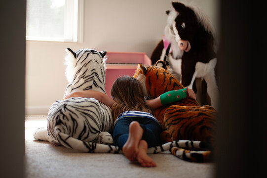Girl with cast hugs her big toy tigers