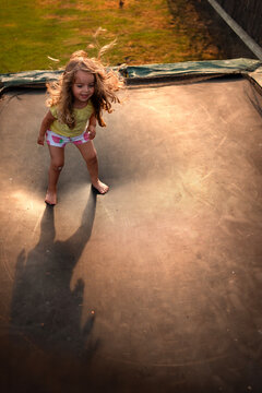 Young girl with flying hair jumping on a trampoline