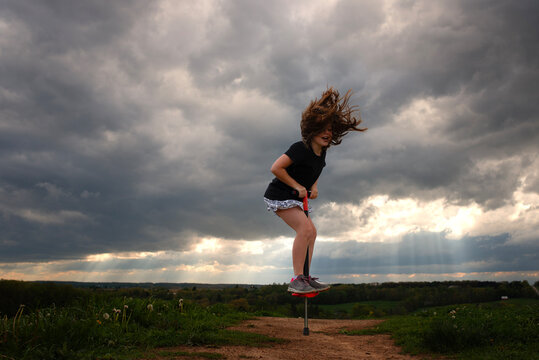 Young girl with hair flying on pogo stick