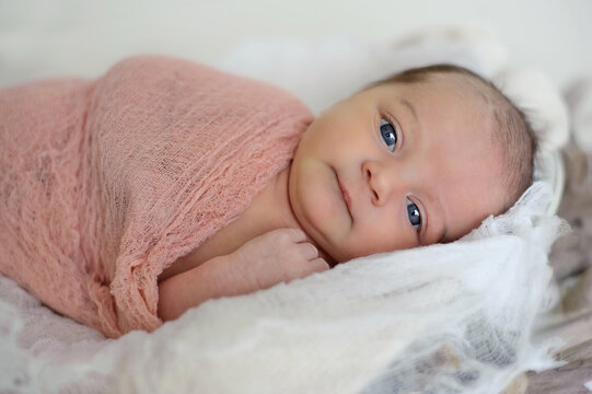 Sweet newborn baby with big blue eyes wrapped up