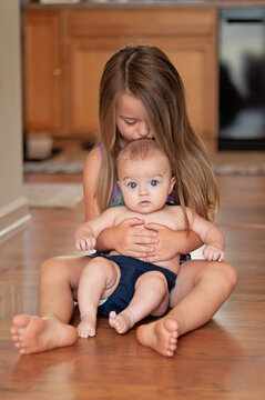 Big sister kisses her baby sibling at home