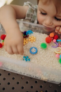 Closeup of toddler hand exploring rice sensory bin