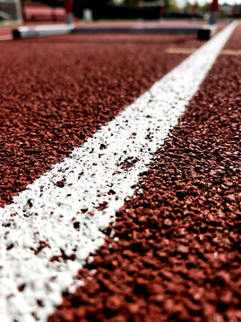 Close Up View of White Boundary Line on Red Running Track Surface