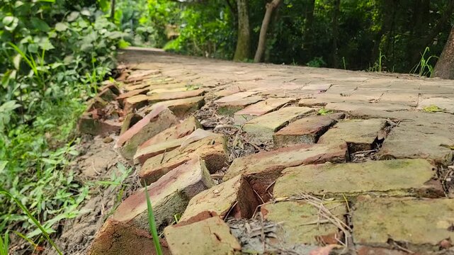 Damaged brick paved walkway pathway with loose uneven bricks in rural village