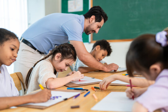 Group of diverse kids coloring paper in classroom at elementary school. 