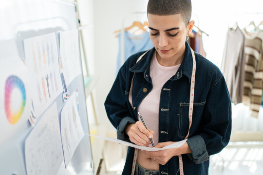 Caucasian young woman working as fashion designer in tailor studio. 