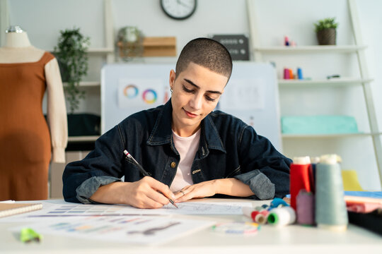 Caucasian young woman working as fashion designer in tailor studio. 