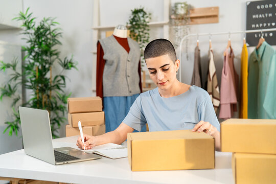 Caucasian woman checking customer orders on laptop in clothing store. 