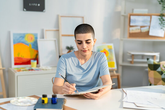 Caucasian beautiful young woman drawing artwork at cozy home studio. 