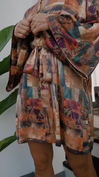 Elegant woman wearing luxury kimono robe in modern tropical home.