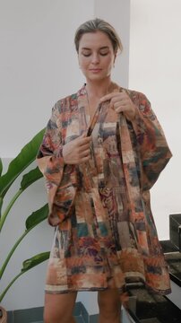 Elegant woman wearing luxury kimono robe in modern tropical home.