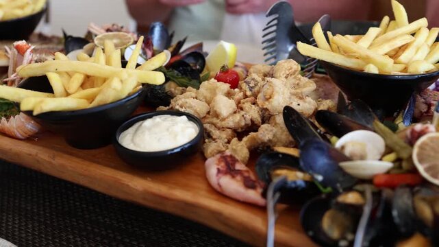 Seafood platter with grilled fish mussels shrimp squid and french fries offers a generous restaurant meal served with lemon and creamy sauce for a relaxing summer dinners