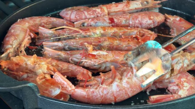 Chef cooking delicious red prawns on a grill pan
