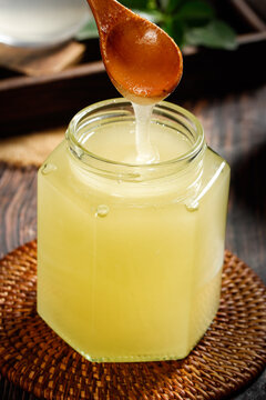 Crystallized Raw Honey with Royal Jelly from Xinjiang Northeastern China Dripping from Wooden Spoon into Glass Jar