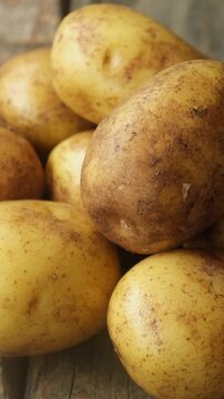 Vertical video. Pile of Fresh Potatoes on a Wooden Background