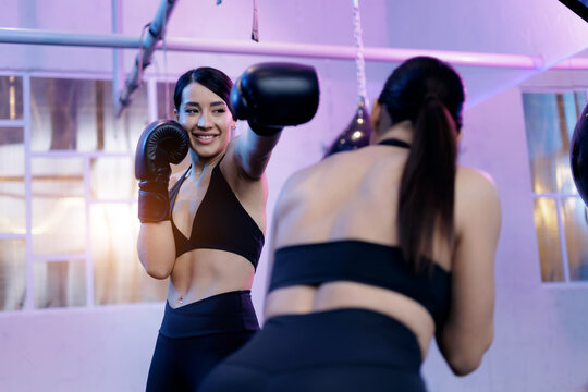 Sport fitness sparring session with coach. Young hispanic female boxers training in modern gym setting, neon light