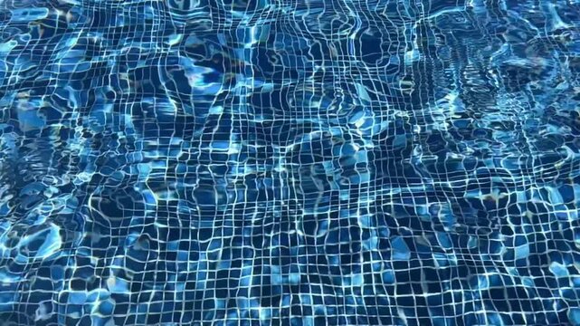 Clear swimming pool water under sunlight. Shimmering ripples moving across the surface. Slow motion video 