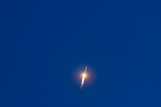 Night sky rocket launch with bright trail against dark blue background