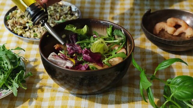 Heathy dinner or breakfast. Diet cuisine. Woman preparing healthy summer shrimp salad pouring olive oil.