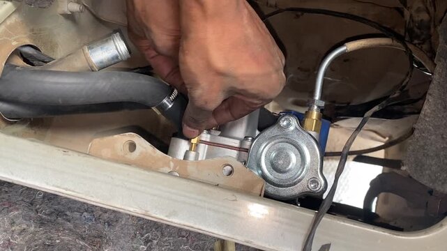 Mechanic hands adjusting brass fitting on CNG vehicle reducer engine