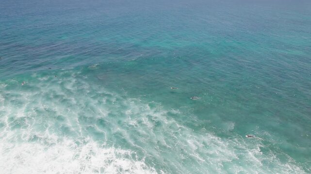 Surfers Scattered in Deep Blue Water Beyond Breaking White Waves at Red Bluff Western Australia Aerial Drone Shot