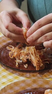Vertical video. Food prep. Female hands peeling boiled tiger shrimp. Eating seafood.