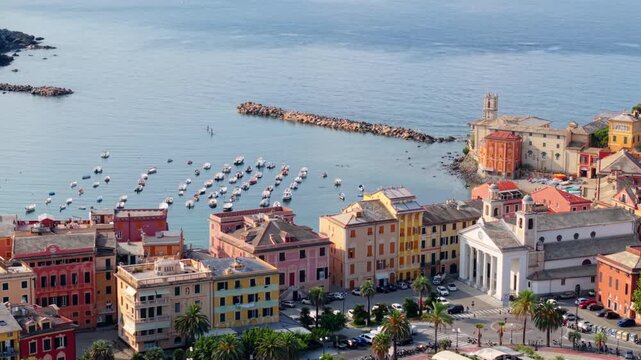 Wide aerial view of colorful seaside buildings, boats moored in a calm Italian harbor