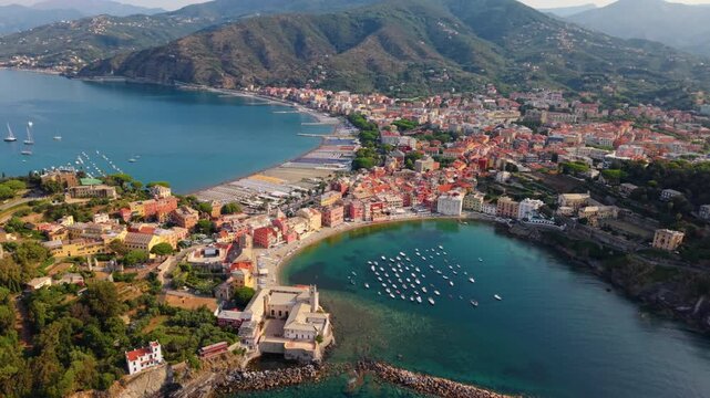 Aerial view of boats in a bay by colorful waterfront buildings and surrounding hills