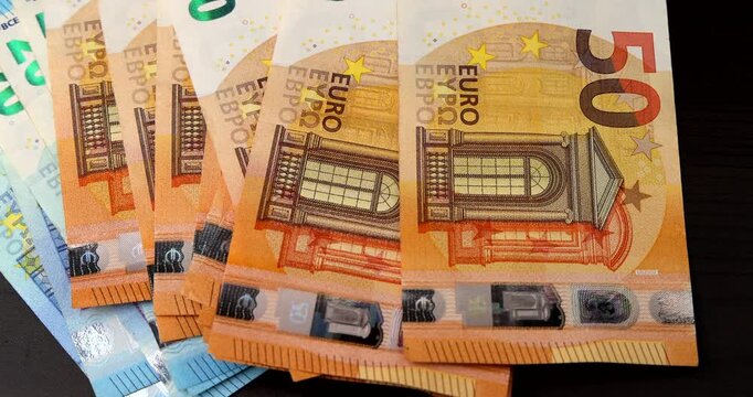 A top down perspective of hands organizing and counting fifty euro cash notes while turning slowly, showing European monetary growth and budget.