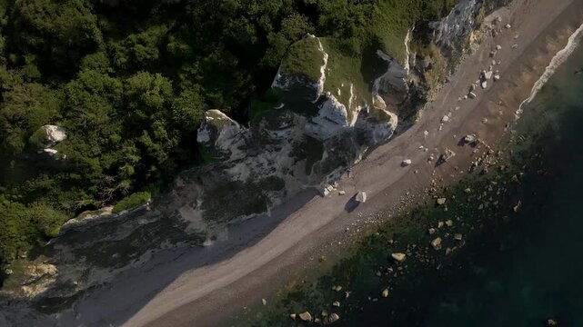 Aerial footage of Seaton cliffs showing the unique white chalk landscape of the Jurassic Coast. Overhead view captures untouched nature, ocean textures, dramatic meeting point between cliffs and sea.