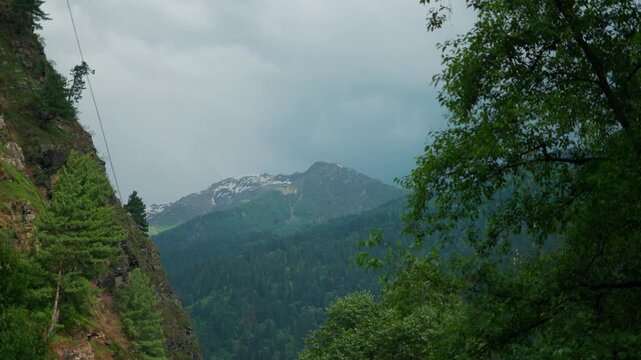 4K Landscape shot of dark stormy clouds above the snowy Himalayan mountain peak during the monsoon season as seen from Manali in Himachal Pradesh, India. Scenic natural background with copy space.