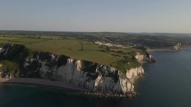 Aerial shot of the White Cliffs of Seaton showing the coastline curving along the sea. The cinematic view captures dramatic cliffs, ocean reflections, and the scenic landscape of Devon&rsquo;s famous coast.