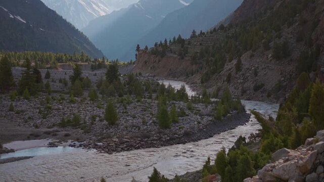 4K Landscape shot of Miyar river flowing in the Himalayan mountain valley with snow covered mountain peaks during the sunset as seen from Miyar Valley in Lahaul, Himachal Pradesh, India.