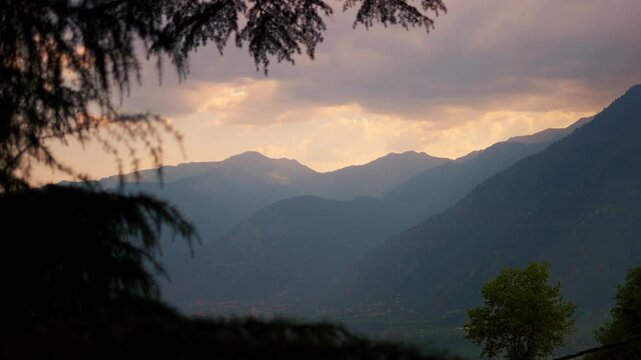 4K shot of Himalayan mountain range during the sunset in monsoon season as seen from Soyal village near Manali in Himachal Pradesh, India. Scenic sunset with clouds in the sky after rain.