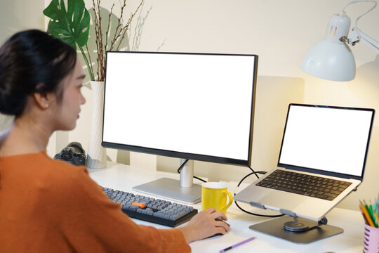 Creative designer focused on her project using a graphic tablet and dual monitors. Bright workspace with a contemporary setup and an inspiring atmosphere