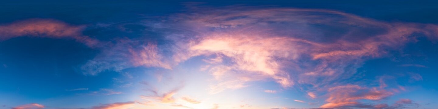 Sunset sky panorama featuring vibrant pink and orange clouds against a deep blue evening heaven with copy space for design