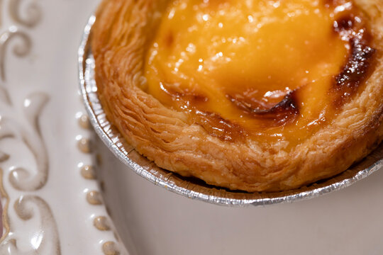 Delicious freshly baked Portuguese egg tart in foil container close up