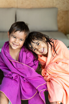 Two white children wrapped in towels smiling indoors in Madrid, Spain