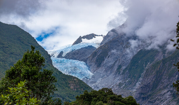 Franz Josef Glacier, Kā Roimata o Hine Hukatere, Gletscherzunge im Talkessel, Suedliche Alpen, Suedinsel, Neuseeland, Regenwald im Vordergrund, tief haengende Wolken