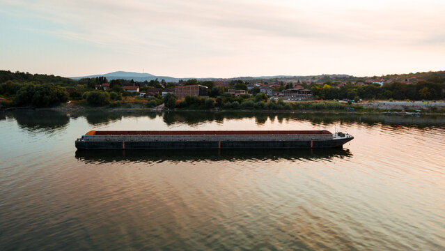 An empty river transport barge on the Danube River during a sunset. Aerial view of an empty river transport barge. Transport barge